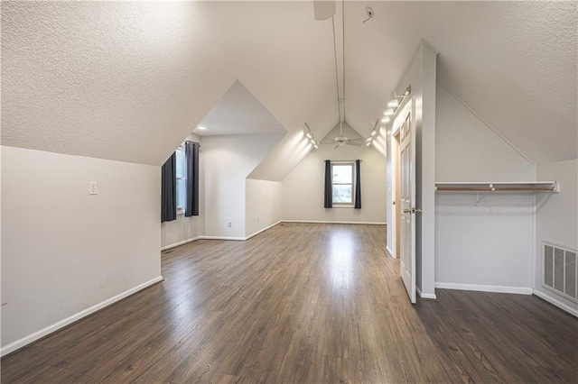 additional living space with a textured ceiling, dark hardwood / wood-style flooring, vaulted ceiling, and ceiling fan