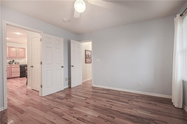 unfurnished bedroom with multiple windows, ceiling fan, and hardwood / wood-style floors