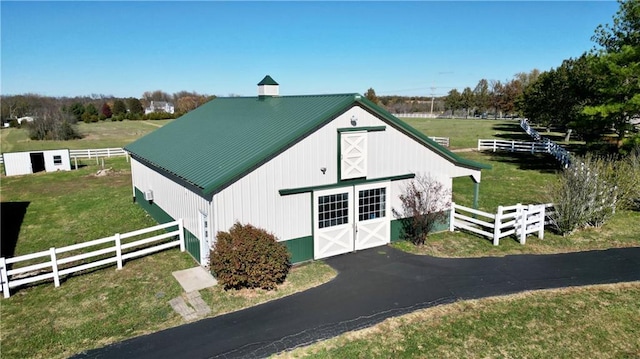 view of outdoor structure with a lawn and a rural view