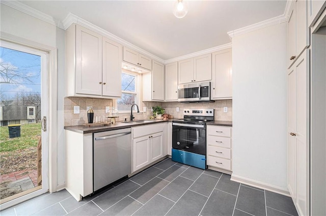 kitchen featuring white cabinetry, sink, decorative backsplash, dark tile patterned flooring, and appliances with stainless steel finishes