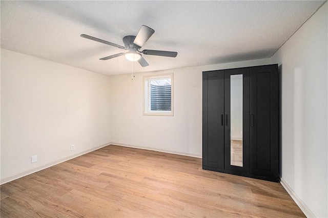 unfurnished bedroom featuring ceiling fan, light hardwood / wood-style floors, and a textured ceiling