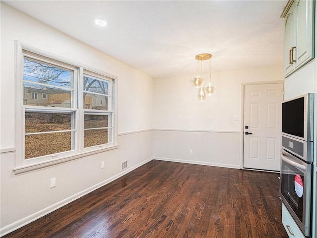 spare room featuring dark wood-type flooring and a notable chandelier