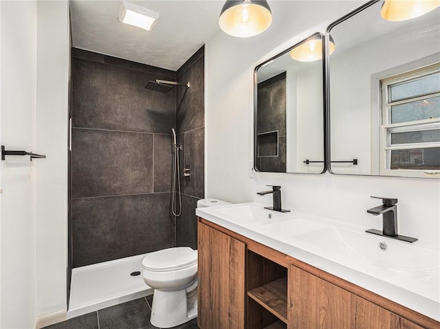 bathroom with a tile shower, tile patterned flooring, vanity, and toilet