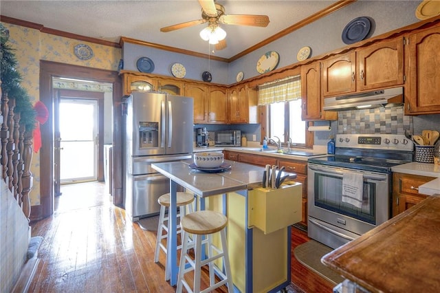 kitchen featuring backsplash, crown molding, stainless steel appliances, and a breakfast bar area