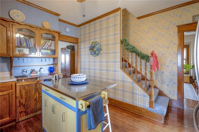 kitchen with hardwood / wood-style flooring, a kitchen island, ornamental molding, and a breakfast bar area