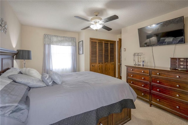 bedroom with a textured ceiling, ceiling fan, light carpet, and a closet