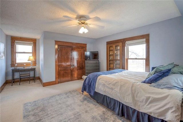 bedroom with multiple windows, ceiling fan, carpet floors, and a textured ceiling