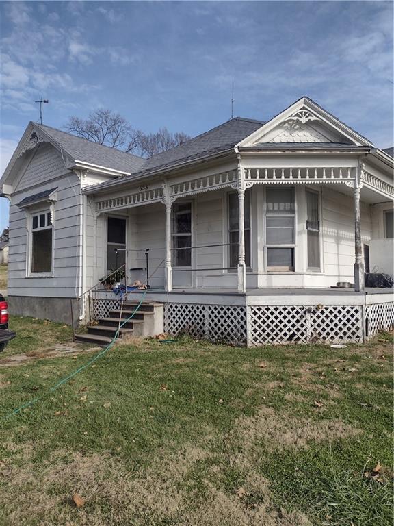 533 4th St, Barnard, MO 64423 - view of side of home featuring covered porch, a lawn, and roof with shingles