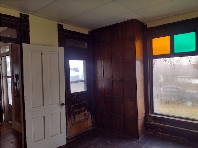 entryway featuring a paneled ceiling, dark hardwood / wood-style floors, and wood walls