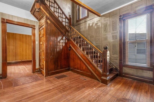 stairs featuring crown molding, wood walls, and hardwood / wood-style flooring