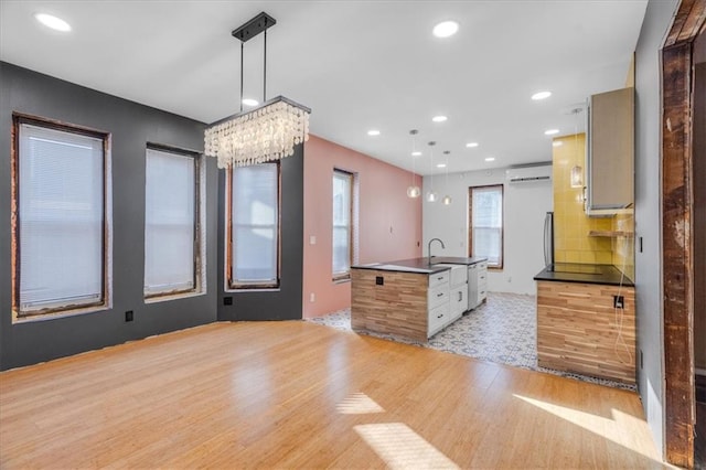 kitchen featuring sink, hanging light fixtures, a kitchen island with sink, and light wood-type flooring