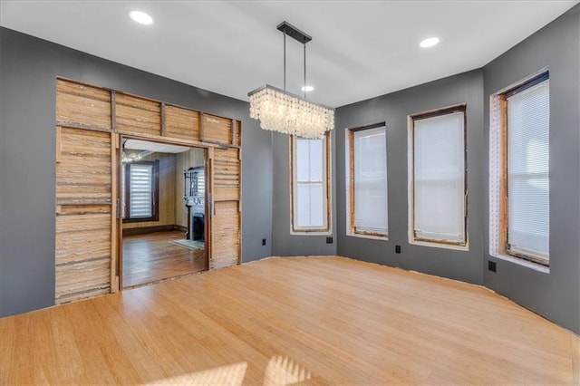 unfurnished dining area featuring a chandelier, a fireplace, and wood-type flooring