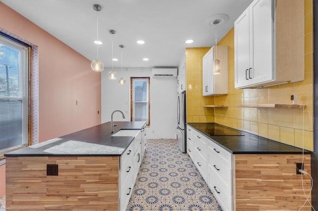 kitchen featuring white cabinets, decorative light fixtures, stainless steel refrigerator, and sink