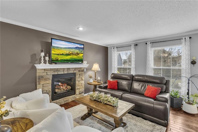 living room with hardwood / wood-style flooring, a fireplace, ornamental molding, and a textured ceiling