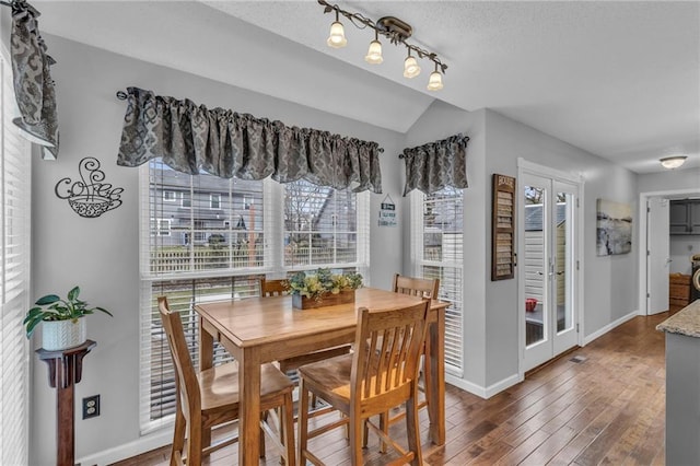 dining space with vaulted ceiling, dark hardwood / wood-style floors, and track lighting