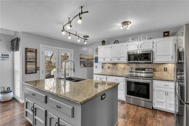 kitchen featuring appliances with stainless steel finishes, sink, a center island with sink, and dark stone counters