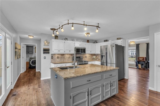 kitchen featuring sink, white cabinetry, light stone counters, stainless steel appliances, and washer / clothes dryer