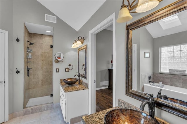 bathroom featuring independent shower and bath, lofted ceiling with skylight, vanity, and tile patterned floors