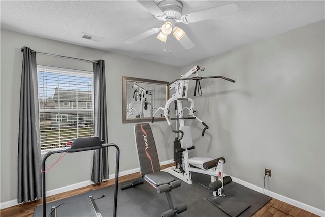 exercise room with ceiling fan and a textured ceiling