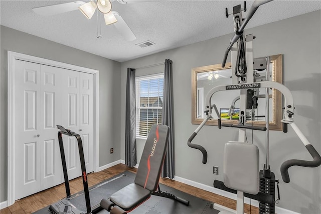 exercise area with ceiling fan, hardwood / wood-style floors, and a textured ceiling