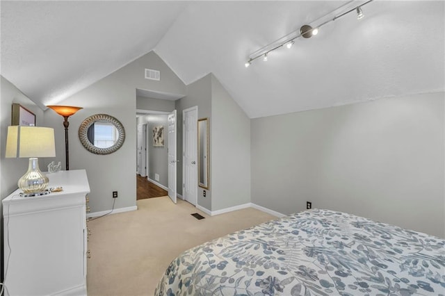 carpeted bedroom featuring vaulted ceiling and rail lighting