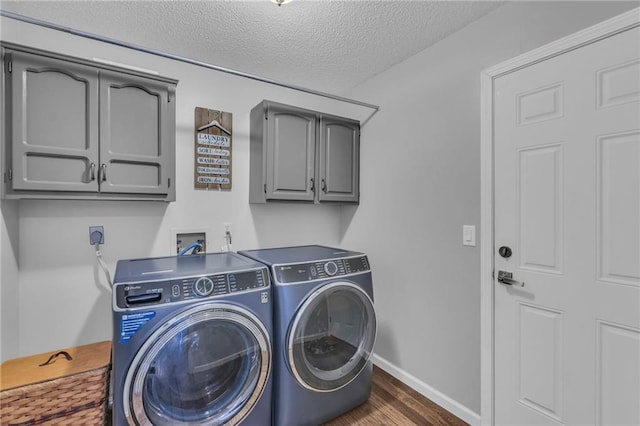 clothes washing area featuring cabinets, dark hardwood / wood-style floors, washer and dryer, and a textured ceiling