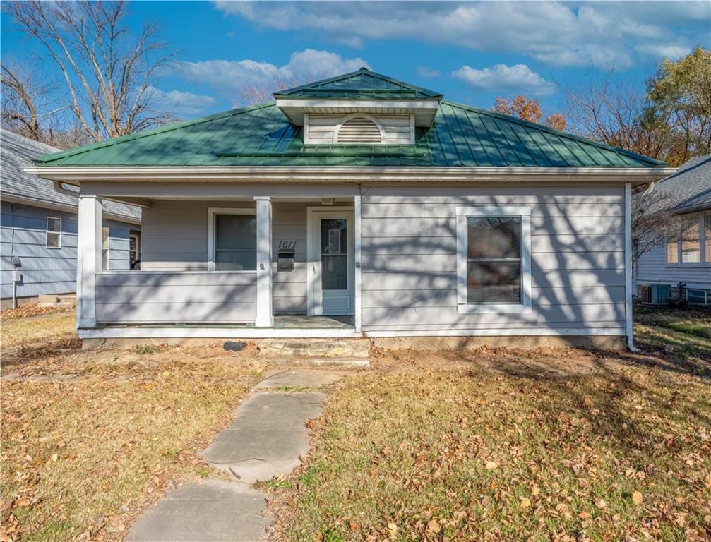 bungalow-style home with covered porch, central AC, and a front lawn