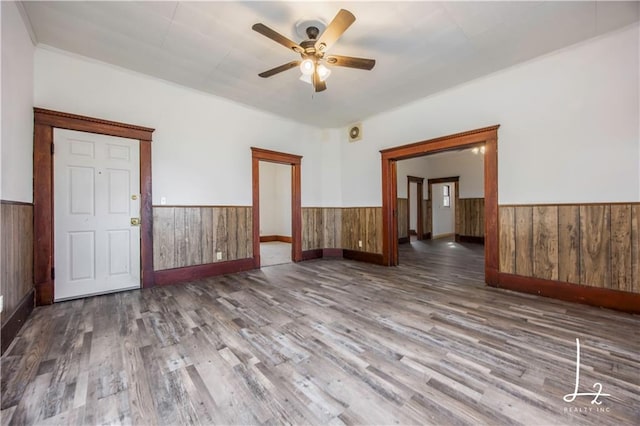 spare room with wood walls, ceiling fan, and wood-type flooring