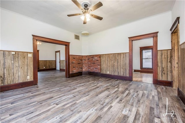 unfurnished room featuring wooden walls, ceiling fan, and wood-type flooring