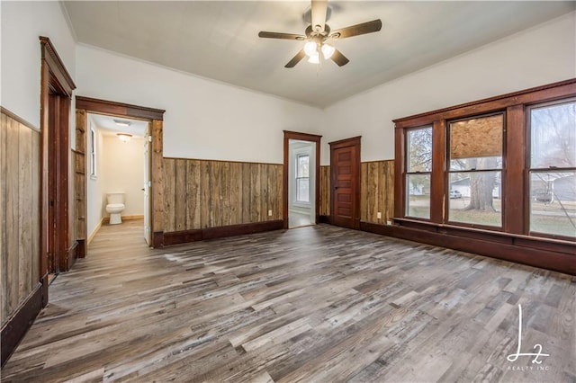 unfurnished room featuring wood walls, ceiling fan, and hardwood / wood-style flooring