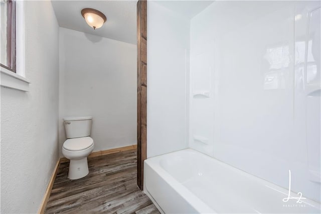 bathroom featuring shower / washtub combination, hardwood / wood-style floors, and toilet