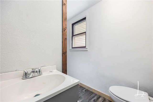 bathroom with toilet, sink, and hardwood / wood-style flooring