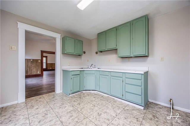 kitchen with green cabinets, sink, and light hardwood / wood-style flooring