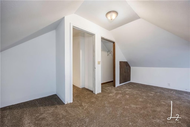 bonus room with dark carpet and lofted ceiling