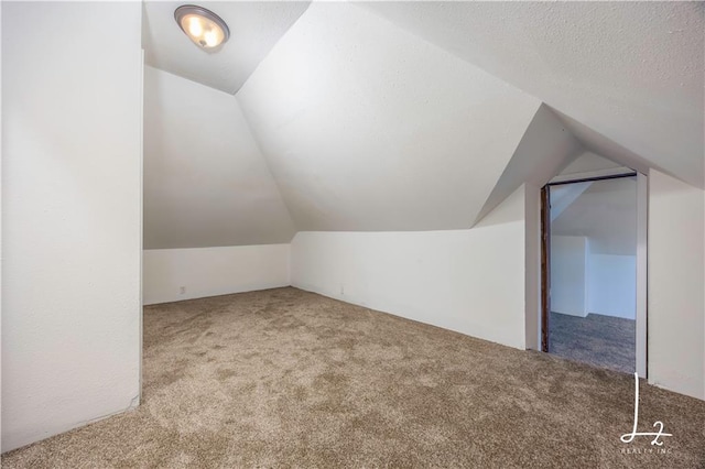 additional living space with a textured ceiling, carpet floors, and lofted ceiling