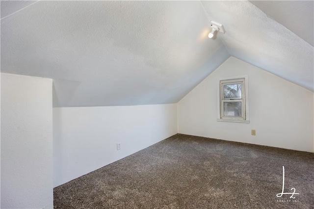 bonus room featuring a textured ceiling, carpet floors, and lofted ceiling