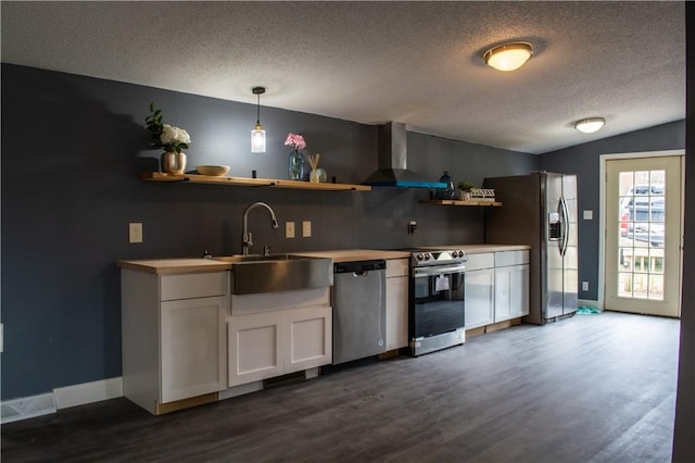 kitchen with wall chimney exhaust hood, stainless steel appliances, pendant lighting, lofted ceiling, and white cabinets