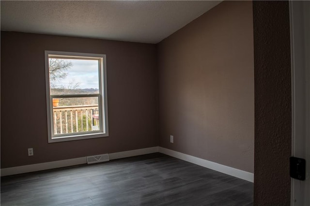 unfurnished room featuring a textured ceiling and dark hardwood / wood-style floors