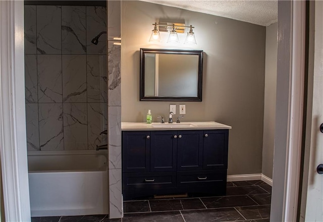 bathroom with vaulted ceiling, vanity, tiled shower / bath combo, and a textured ceiling