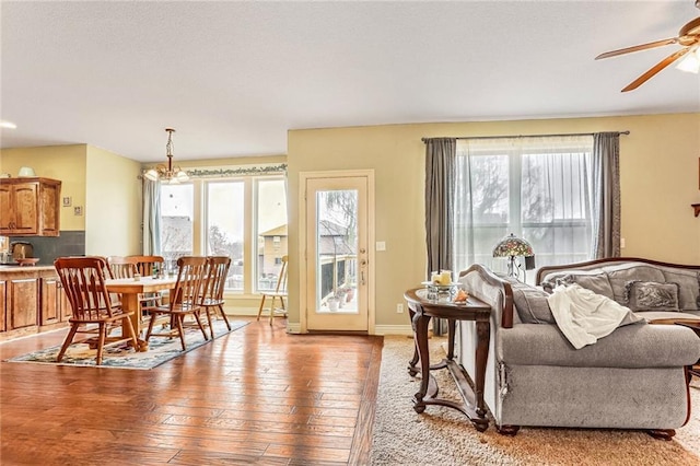 living room featuring a wealth of natural light, light hardwood / wood-style floors, and ceiling fan with notable chandelier