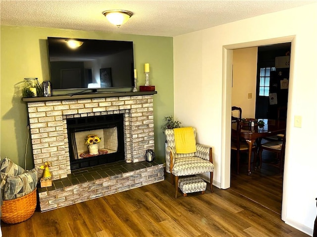 sitting room featuring wood-type flooring, a textured ceiling, and a brick fireplace