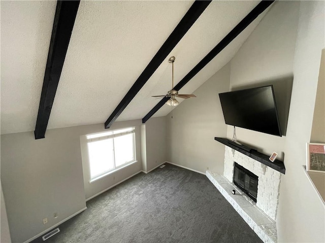 unfurnished living room with a fireplace, carpet floors, vaulted ceiling with beams, ceiling fan, and a textured ceiling