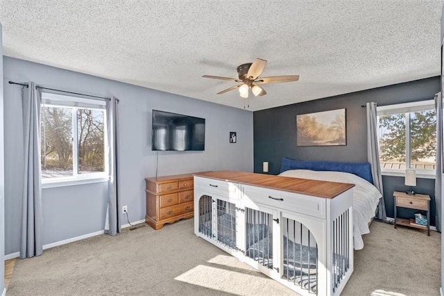 bedroom featuring light colored carpet, a textured ceiling, and ceiling fan