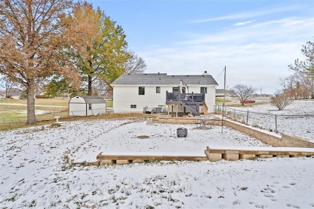 snow covered house featuring a storage unit and a deck