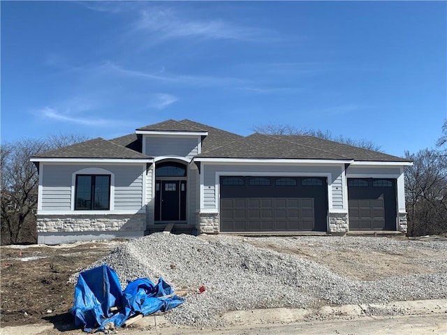 view of front of house featuring stone siding, a garage, driveway, and roof with shingles