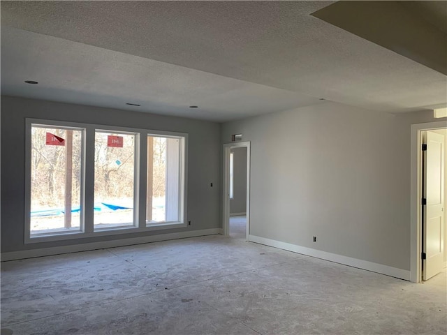 empty room featuring a textured ceiling and baseboards