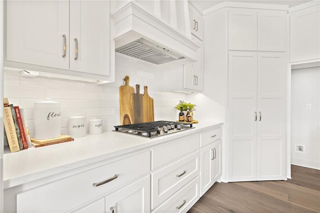 kitchen featuring backsplash, stainless steel gas stovetop, light countertops, custom exhaust hood, and dark wood-style flooring