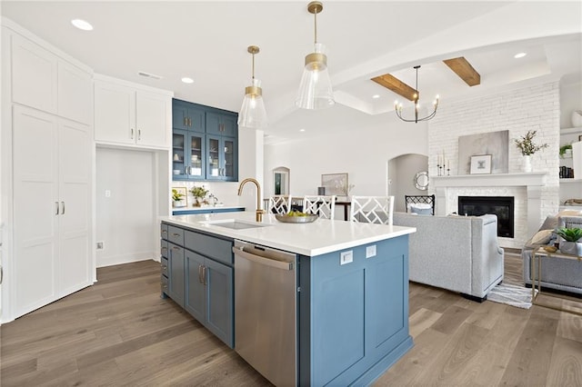 kitchen with blue cabinets, arched walkways, dishwasher, and a sink