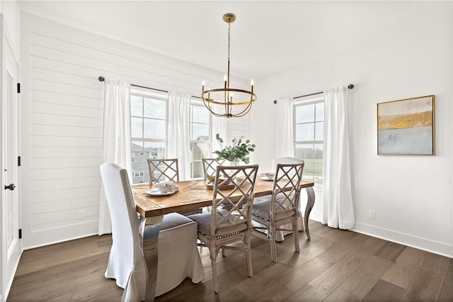 dining space with dark wood finished floors, a chandelier, and baseboards