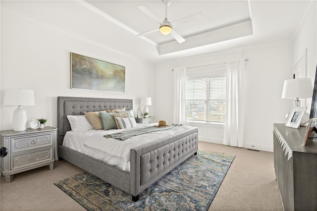 bedroom featuring baseboards, a raised ceiling, light colored carpet, and a ceiling fan